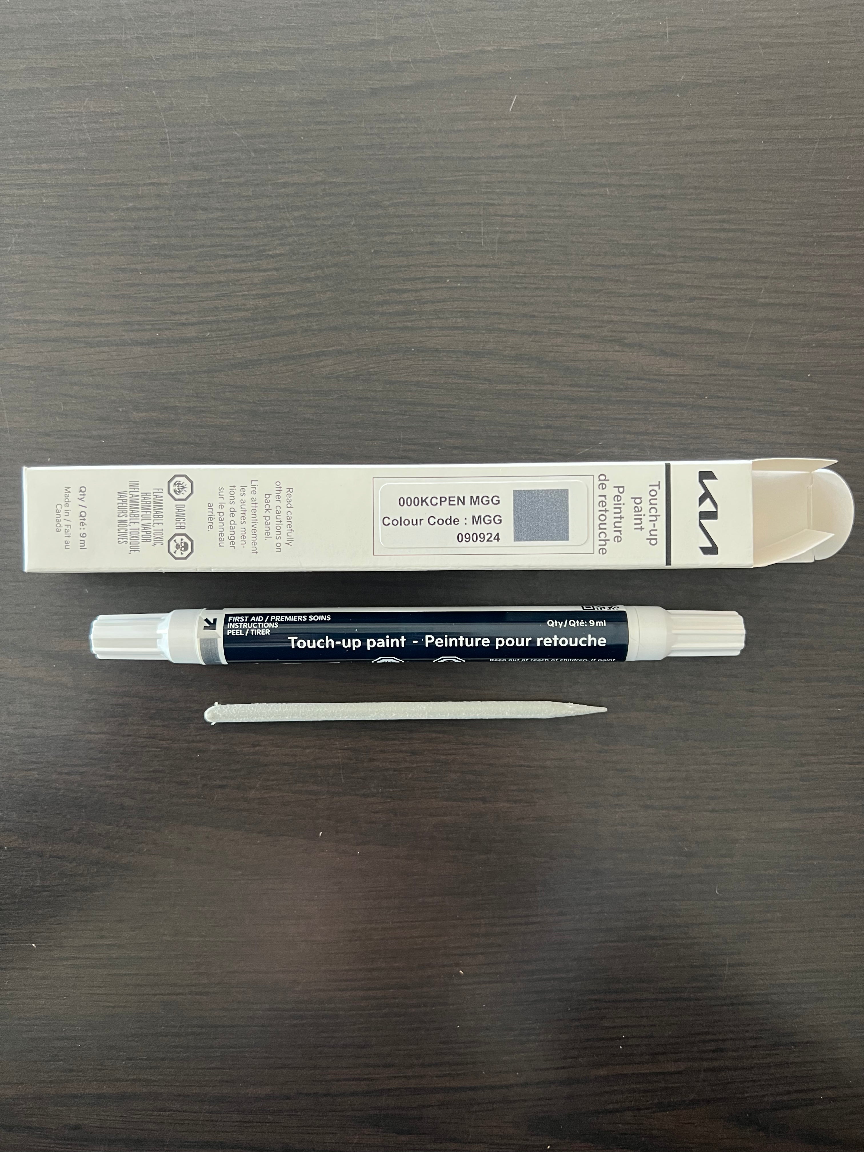 Touch-up Matte grey MGG paint pen and its packaging on a wooden surface 